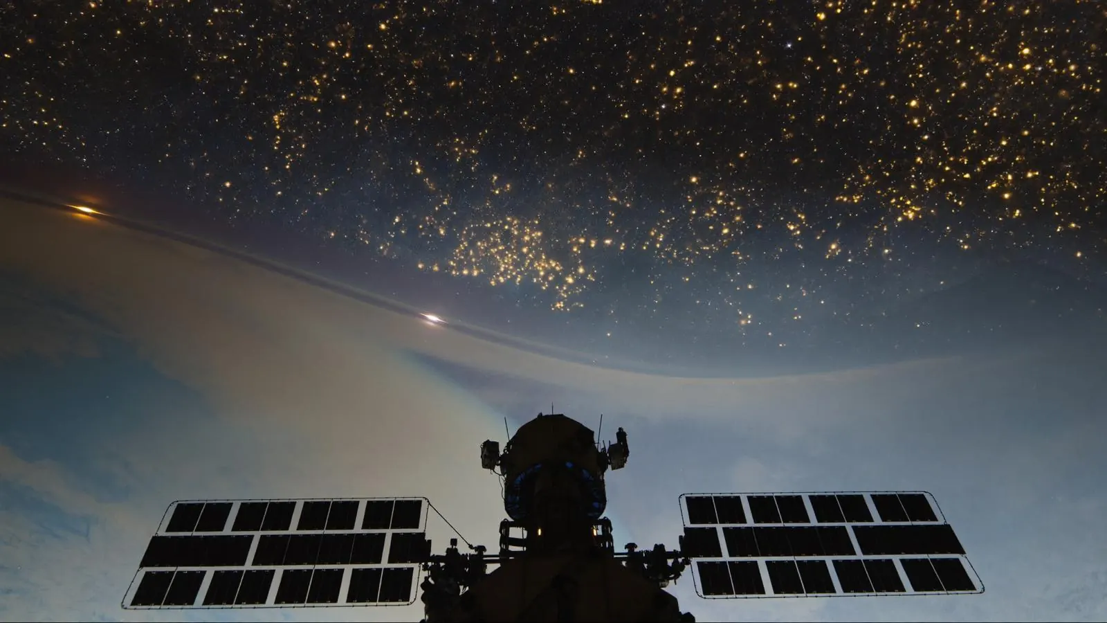 An orbital station module with solar panels above a planet’s night side, city lights below and a soft glowing transit corridor arcing across the dark.